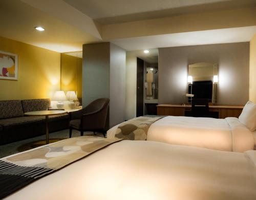 a hotel room with two beds and a living room at Hotel New Otani Hakata in Fukuoka