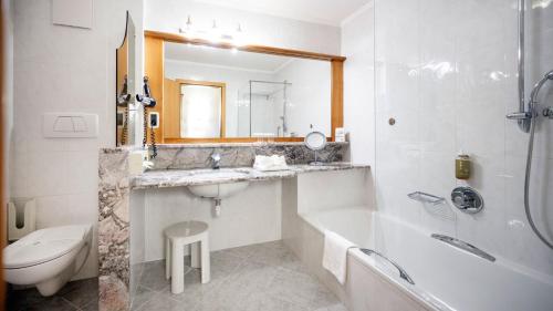 a bathroom with a sink and a tub and a toilet at Activehotel Diana in Siusi