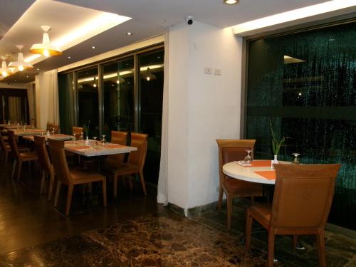 a restaurant with tables and chairs and a large window at Alasra Suites in Ulot
