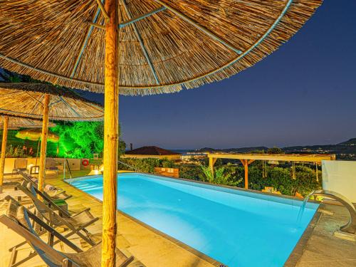 a swimming pool with a straw umbrella and chairs at Holiday Sea View Villas in Katastárion
