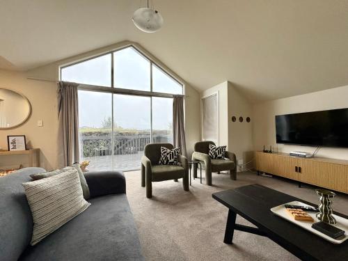 a living room with a couch and a large window at Mountain Views on the Reserve in Wanaka