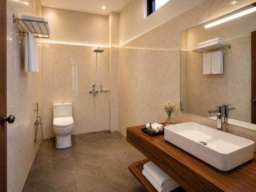 a bathroom with a sink and a toilet and a mirror at Hotel Valna Estate Himalyan View Kausani By HRG in Kausani