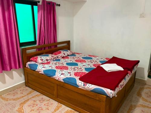 a bedroom with a bed with a red and blue quilt at SH Guest House Malvan in Malvan