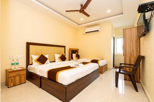 a bedroom with two beds and a chair in it at Meeraa Residency in Rāmeswaram