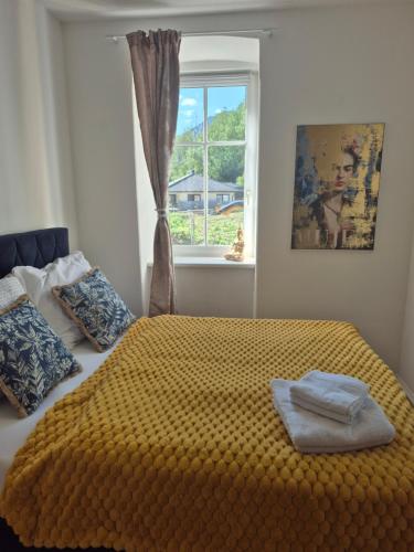 a bedroom with a bed with a yellow blanket and a window at Apartment Gletscher & Fluß in Penk