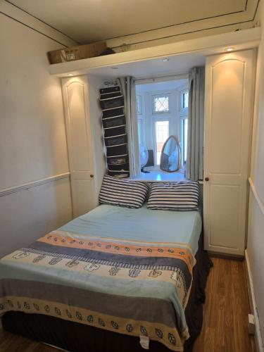 a small bedroom with a bed with a window at Wembley Stadium Room with Parking and Breakfast in London