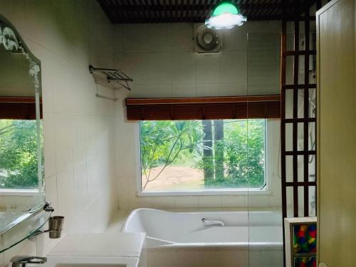 a bathroom with a bath tub and a window at Saiyok River House in Sai Yok