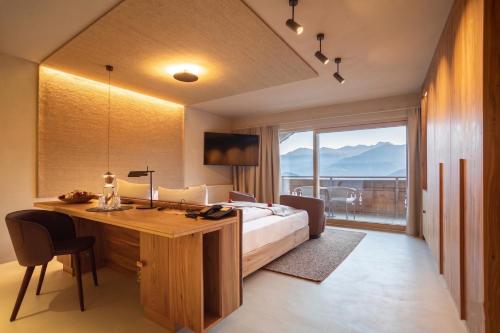a bedroom with a bed and a desk and a window at Hotel Schönblick in Rodengo