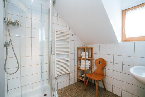 a bathroom with a shower and a sink and a chair at Gästehaus Berger in Tröpolach