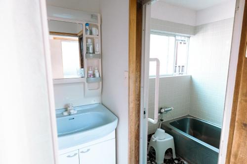 a bathroom with a sink and a bath tub at 民泊豊久 in Nigō