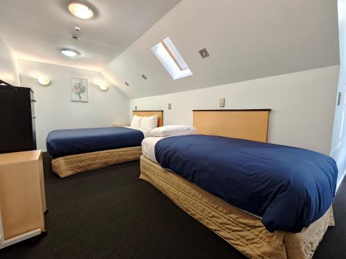 a bedroom with two beds with blue sheets and a tv at Athena Motel in Christchurch