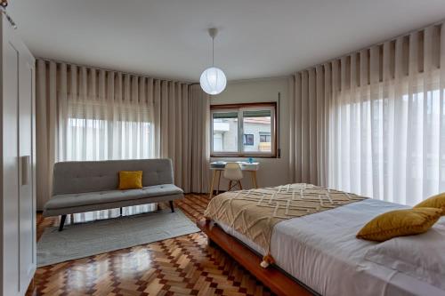 a bedroom with a bed and a chair and a window at Alegria Beach House in Vila do Conde