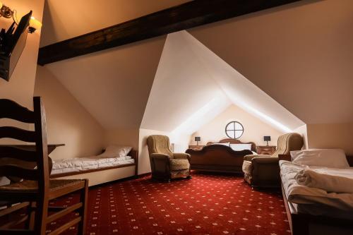 a room with two beds and chairs in a attic at Dworek Opartowo in Rajgród