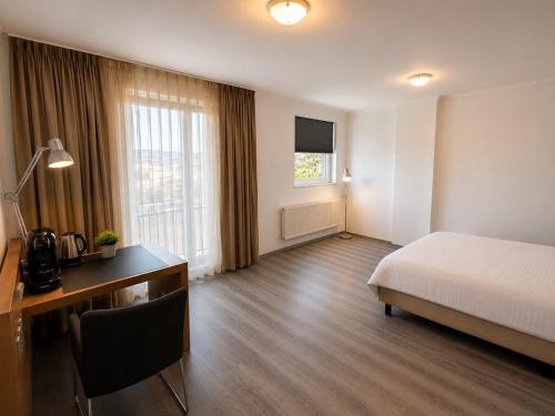 a hotel room with a bed and a desk and window at M14 Stay Cluj in Cluj-Napoca