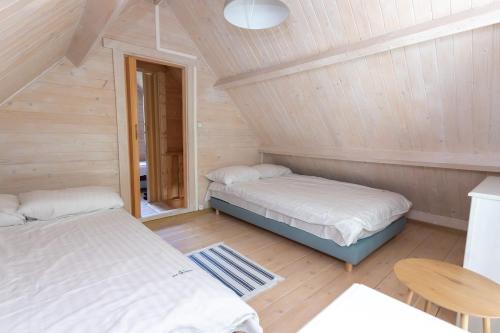 two beds in a room with wooden walls at Domki Pod Sosnami in Rowy