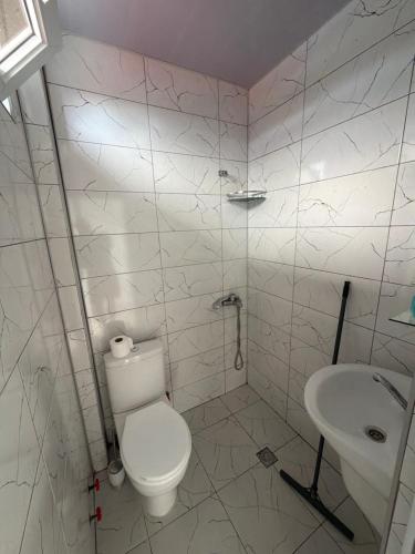 a white bathroom with a toilet and a sink at Hotel Like Mari in P'ichvnari