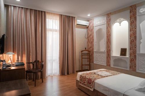 a bedroom with a bed and a desk and a window at Omar Khayyam Hotel in Bukhara