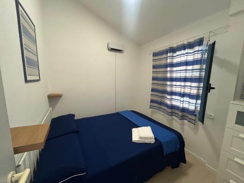 a small room with a blue bed and a window at Blu 31 Marcelli in Marcelli