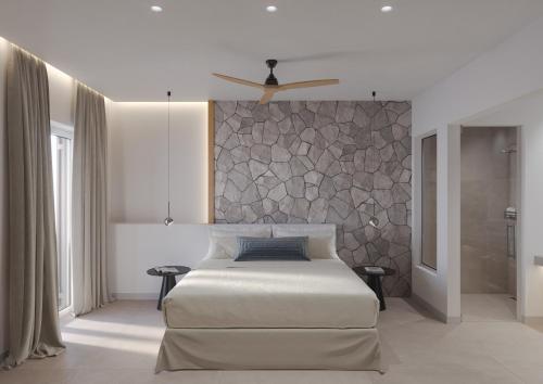 a bedroom with a bed and a stone wall at Vilos Luxury Suites in Pollonia