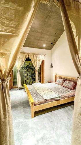 a bedroom with a bed in a room with curtains at Te Retreat in Hà My Tây (2)