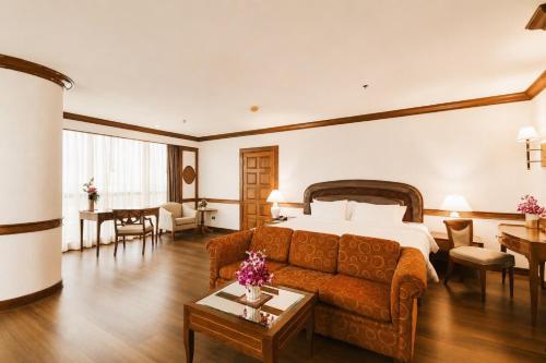a hotel room with a bed and a couch at The Twin Lotus Hotel in Nakhon Si Thammarat