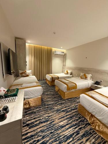 a hotel room with three beds and a flat screen tv at Johra International Hotel فندق جوهرة إنتر ناشونال in Medina