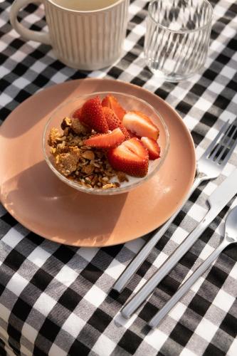 a bowl of granola and strawberries on a plate on a table at Maison d'hôtes le détour en pleine nature in Channay-sur-Lathan