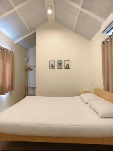 a bed in a room with three pictures on the wall at บ้านตัวเล็กศาลายา in Sathani Wat Suwan