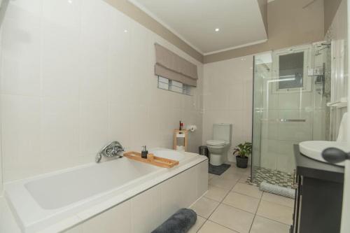 a bathroom with a tub and a shower and a toilet at Crown Oak in Gqeberha