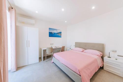 a white bedroom with a pink bed and a desk at Villetta Mami in Ischia