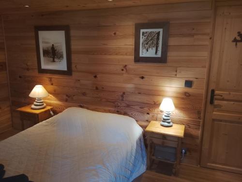 a bedroom with wooden walls and a bed with two lamps at La chambre Nature chez les garçons in Saint-Paul-sur-Yenne