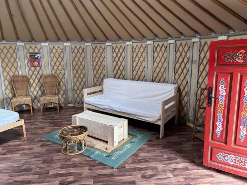 a yurt with a bed and chairs and a red door at Fermily Lodges in Perrières