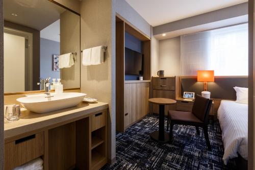 a hotel room with a sink and a bed at Hotel Forza Osaka Kitahama in Osaka