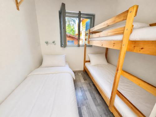two bunk beds in a small room with a window at Nádaspart Vendégház in Zánka