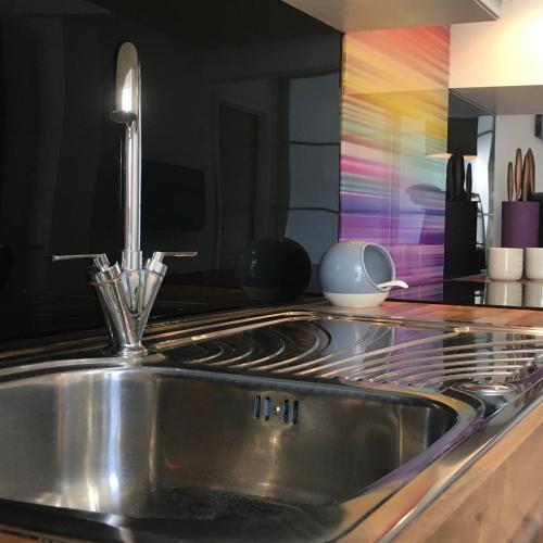 a kitchen with a stainless steel sink and a colorful wall at Over Under Cottage in Holmfirth