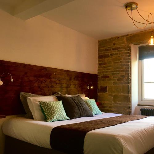 a bedroom with a large bed with a brick wall at Over Under Cottage in Holmfirth
