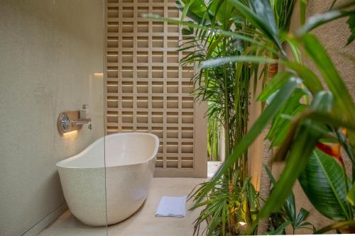 a bathroom with a white tub and some plants at Antonella De Rosa Villas in Nusa Dua
