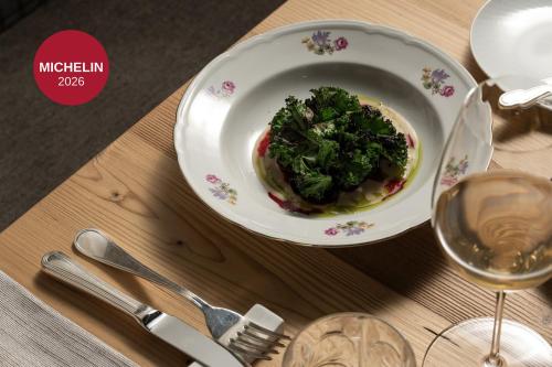 a plate of food with greens in it on a table at Hotel Orso Grigio in Cavalese