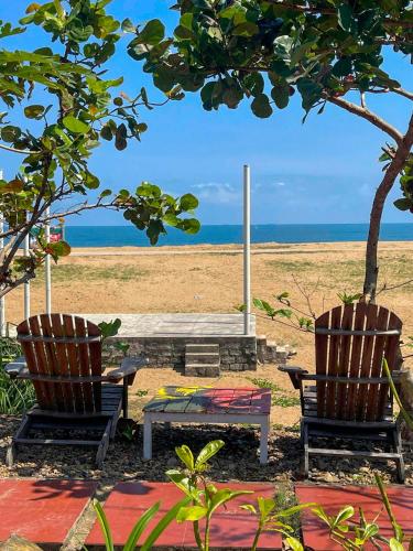 two chairs and a bench in front of a beach at Phu Yen Beachfront Fishing Village Homestay in Tuy Hoa