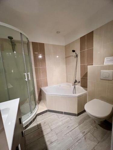 a bathroom with a tub and a toilet and a shower at L'Escale d'Armorique 2 in Languidic