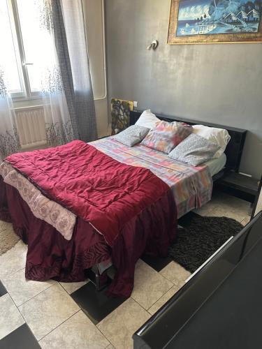 a bed with a red comforter in a bedroom at Laila in Creil