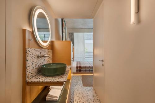 a bathroom with a green sink and a mirror at Dizengoff 99 by Isrotel Design in Tel Aviv