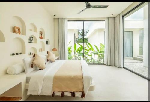 a bedroom with a large bed and a large window at Julie House Lombok in Ekas