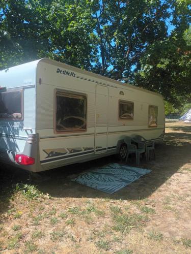 a white trailer parked in a field with a table at Grande caravane in Gergy