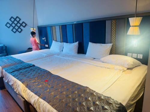 a woman standing next to a large bed in a room at APEC Mandala in Mui Ne
