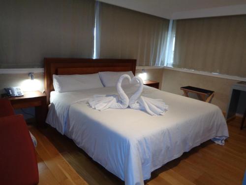 Un dormitorio con una cama con toallas blancas. en Hotel Villa De Betanzos, en Betanzos