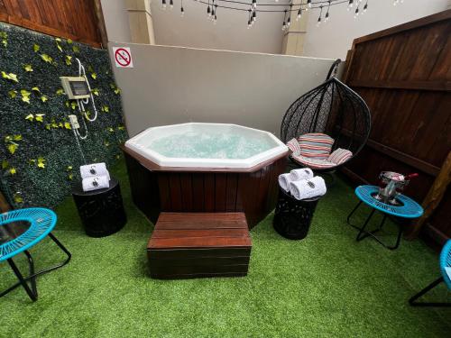 a bath tub in a room with a chair and tables at EDEN BOUTIQUE HOTEL in Kokstad