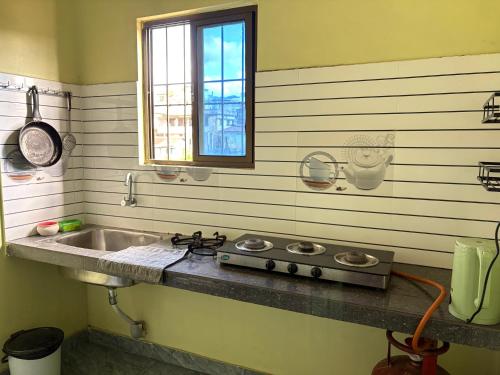 a kitchen with a sink and a window at BeeHive Homestay in Hāflong