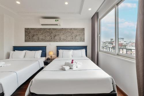two beds in a room with a window at Golden Sun Hotel in Hanoi