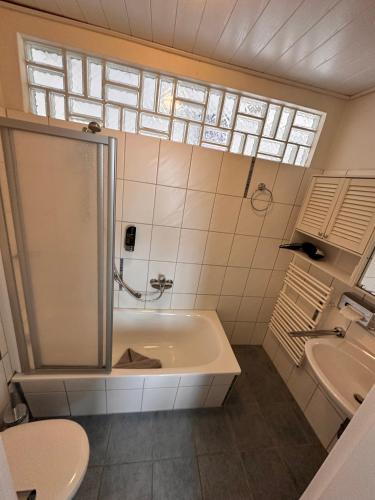 a bathroom with a shower and a tub and a sink at Hotel-Pension Haus Hubertus in Borkum
